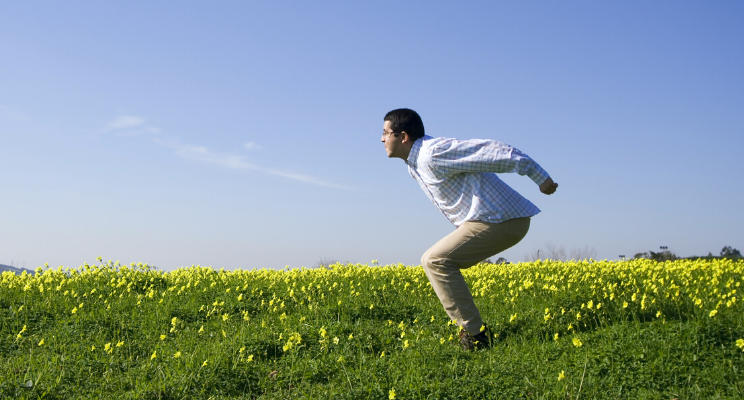 man preparing to jump up in a field of yellow flowers