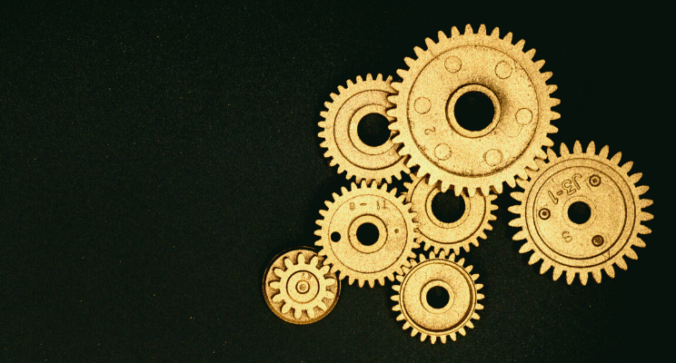 different sized gold gears against black background