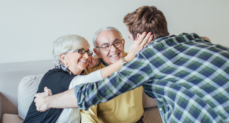 elderly couple embracing a young man