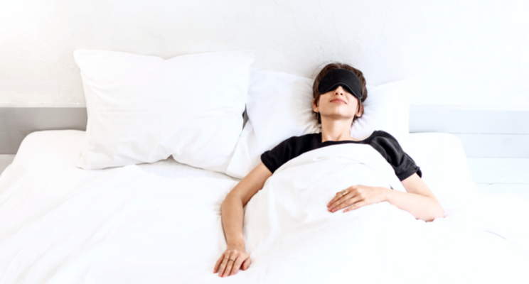 woman wearing black eye mask in a bed