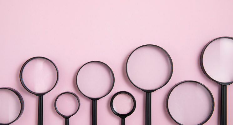 different sized magnifying glasses against a pink background